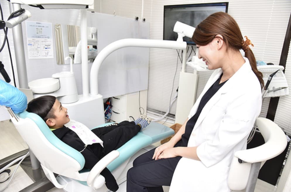 診療チェアのお子さまと話す中村彩華院長